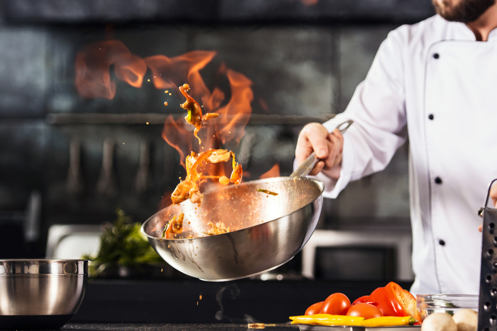 Kok wokt boven fornuis met wokpan